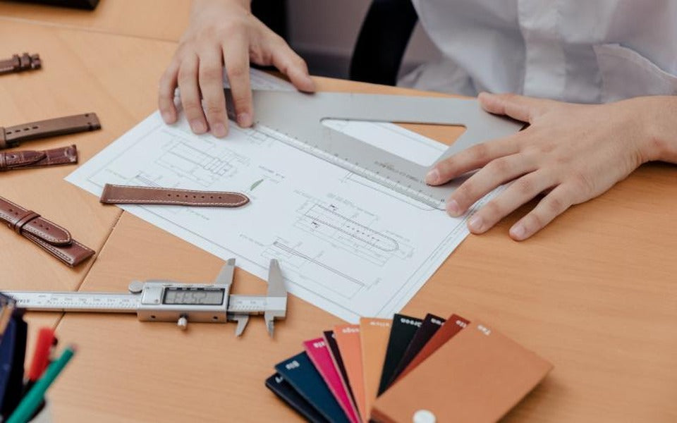 Watchmaker measuring strap dimensions with calipers and technical drawings