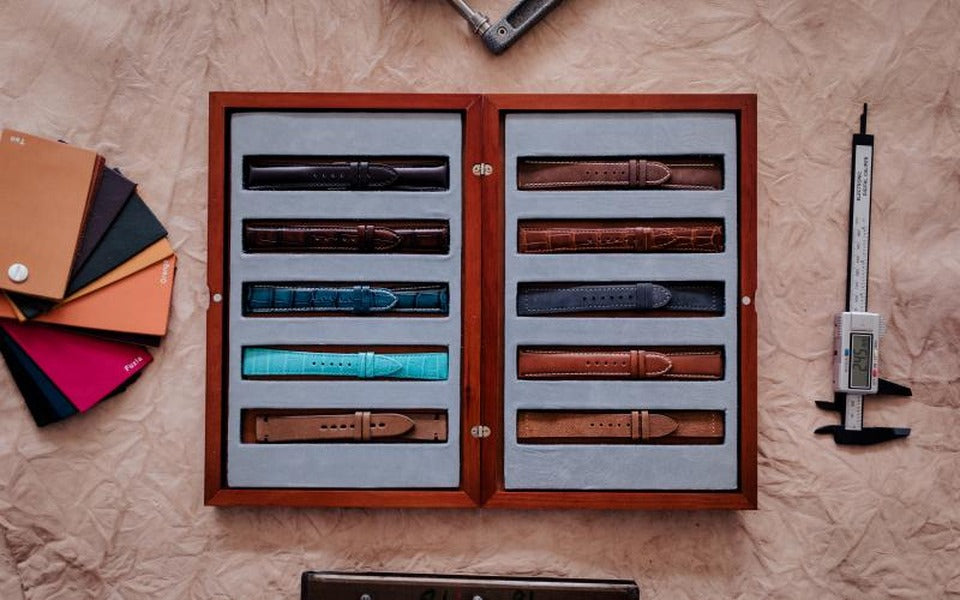 A wooden tray of finished leather watch straps in assorted colors