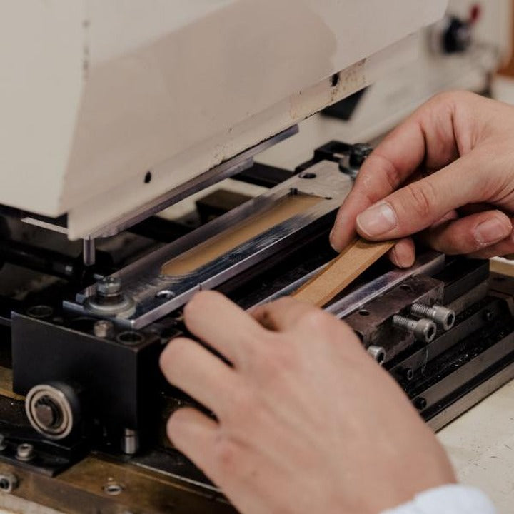 Hand-cutting a leather strap blank on a clicker press